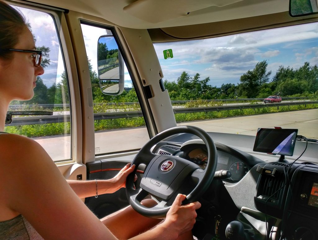 young lady with glasses driving a van on a highway, summer vehicle safety