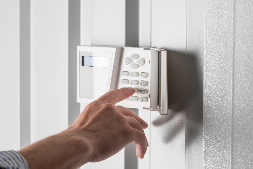 homeowner pushing buttons on a home security system